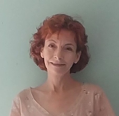 Headshot of a woman smiling. She has short red hair.