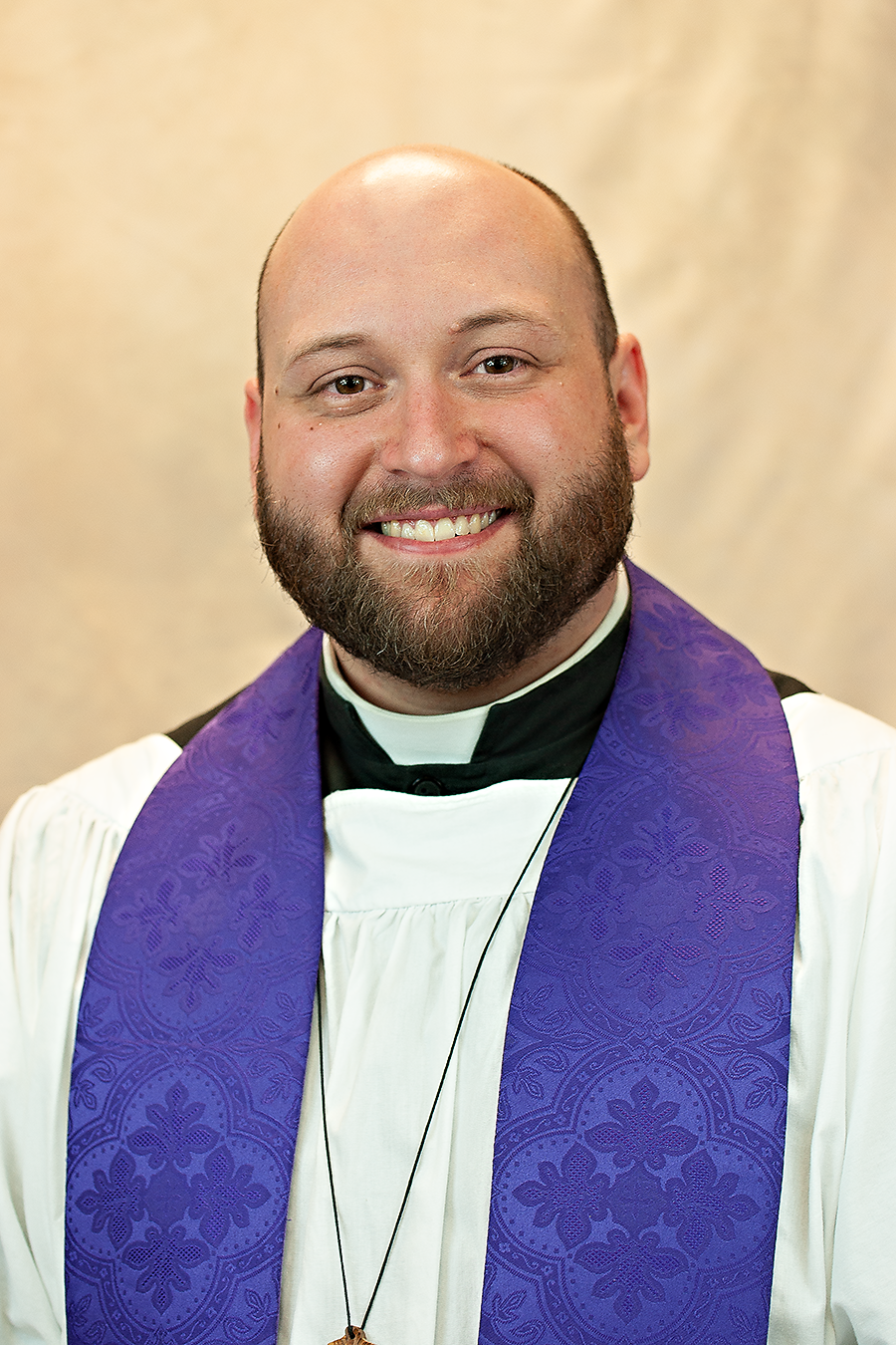 Reverend Bruce Gowe wearing priestly vestments in white and purple.